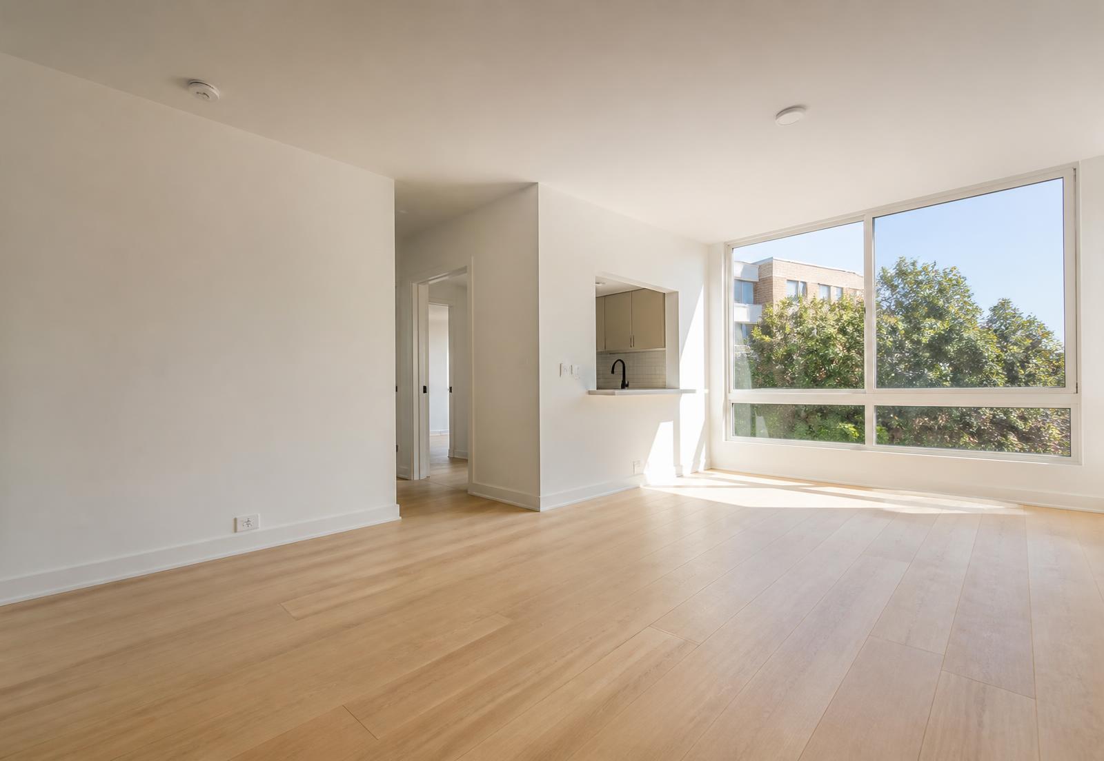 Freshly renovated empty apartment living space with oak floors and natural light